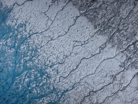 Aerial photograph taken on 24 July 2015 over the southwest portion of the Greenland ice sheet, near Kangerlussuaq. (left) The turquoise color is characteristic of meltwater on the shore of a supraglacial lake. (center) Area from which the lake water has receded, removing impurities and leaving bare ice. (right) Ice and snow covered by surface impurities. Credit: Marco Tedesco