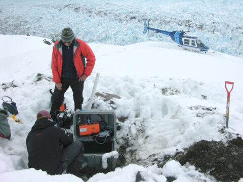 Researchers retrieve data from a seismometer adjacent to Yahtse Glacier. At this ocean-terminating glacier, measurements of background seismic noise revealed how water flow becomes more efficient over the course of a summer. Credit: Timothy Bartholomaus