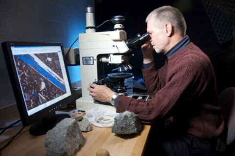 Robert Hazen studies thin slices of rock under a microscope in his lab at the Carnegie Institution in Washington, D. C.
