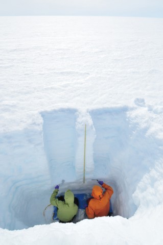 In a pit they dug in south central Greenland, scientists collect samples to investigate how the melting of snow affects the numbers of light-absorbing particles that dot the snow’s exposed surface. Credit: Richard Brandt