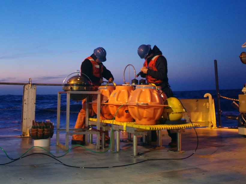 Engineers decommissioning an ocean bottom seismometer and differential pressure gauge