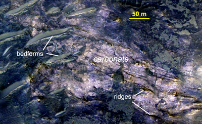 Aeolian bedforms overlie ancient layered, ridged carbonate-rich outcrop exposed in the central pit of Lucaya crater, northwest Huygens basin, Mars.