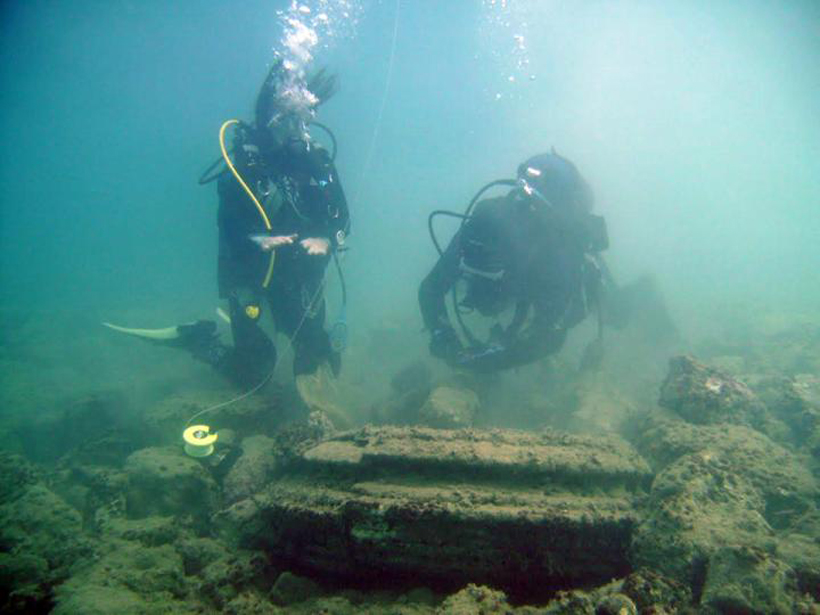 Divers examine faux ancient pillar base.