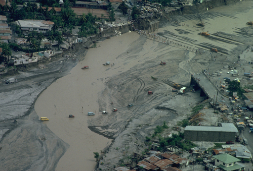 Cars and people traverse a flooded river in June 1991 after lahars wiped out bridges.