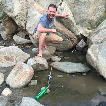 Helium-One geologist takes gas samples at hot spring.