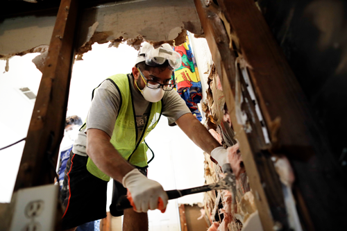 A volunteer removes sodden drywall and insulation at a Houston home flooded by Harvey