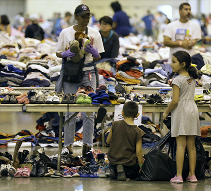 Children evacuated from Harvey’s floodwaters look through donated shoes at a shelter in downtown Houston on 30 August.