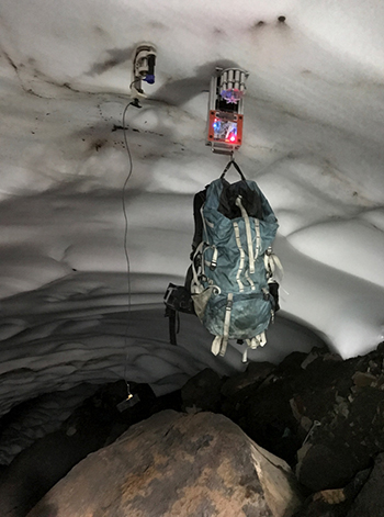 Two prototype robotic “hands” grip an ice cave’s ceiling.