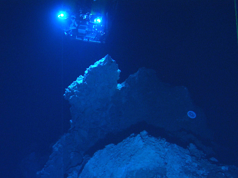 The spotlights of a remotely operated vehicle illuminate carbonate rock spires of the Lost City hydrothermal vent field in the Atlantic Ocean.