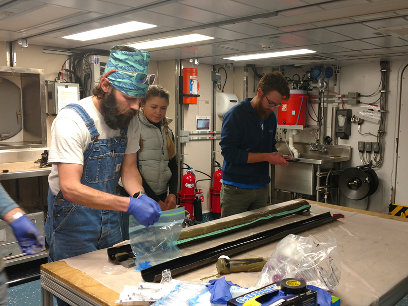 Participants in the UNOLS Chief Scientist Training Cruise split and examine sediment cores during the 2016 expedition.
