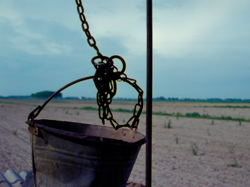 A bucket lies on dry a well in the middle of a farmland in Italy’s Delta Po region