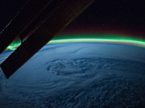 Swirling cloud formation and the aurora borealis over the northern Atlantic Ocean, looking toward the North Pole