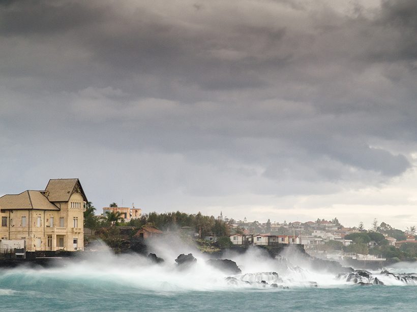 Ocean waves pound the shore of a coastal town in Italy.