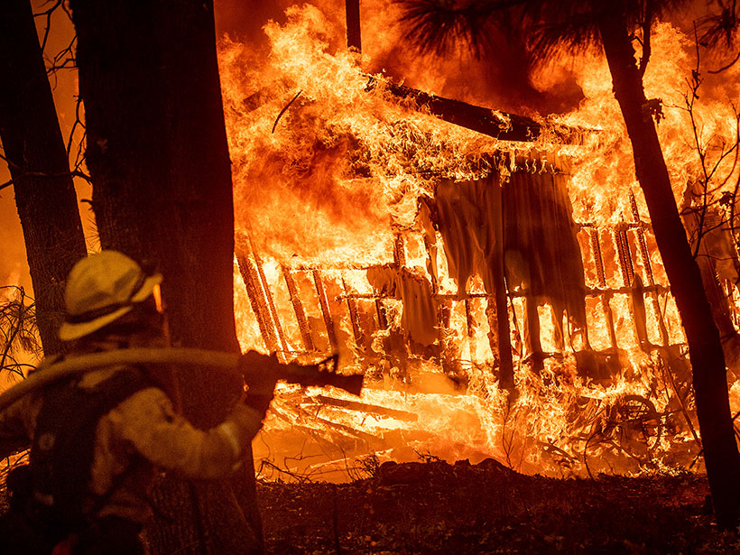 A firefighter looks on as homes burn in Northern California’s Camp Fire earlier in November 2018.