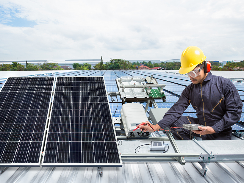 An engineer maintains solar panel equipment on a factory roof.