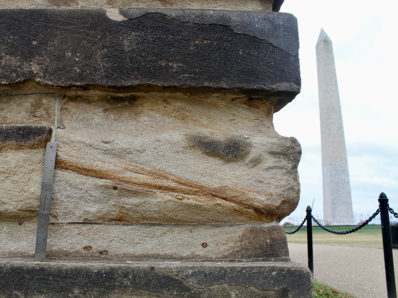 The Washington Monument peeks out from behind a sandstone gatepost