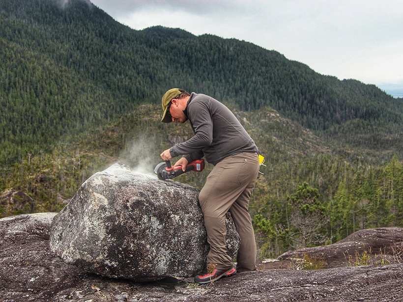 A researcher collects a rock sample for dating