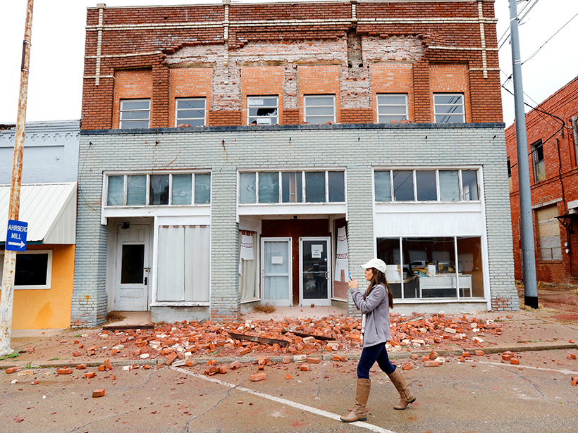 A woman walks past debris from a building damaged by an earthquake in Oklahoma