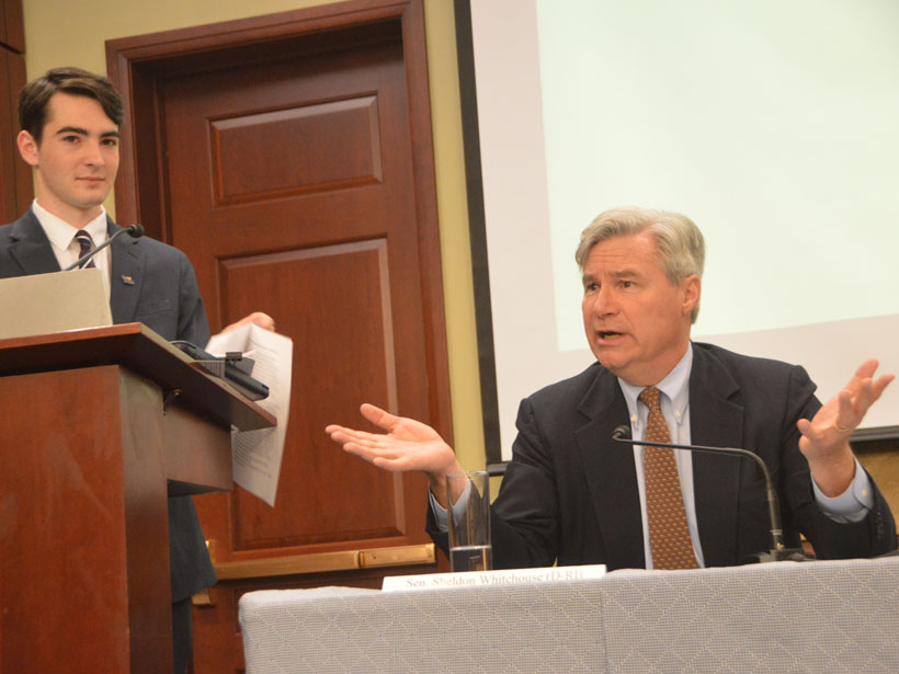 A young white man and an older white man lead a meeting at a podium