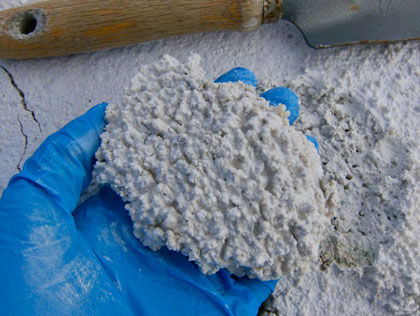 A gloved hand holding a chunk of the white mineral hydromagnesite A gloved hand holding a chunk of the white mineral hydromagnesite