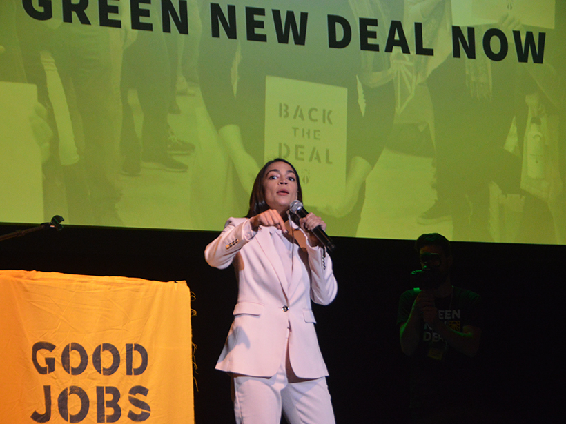 Rep. Alexandria Ocasio-Cortez gestures from a podium.
