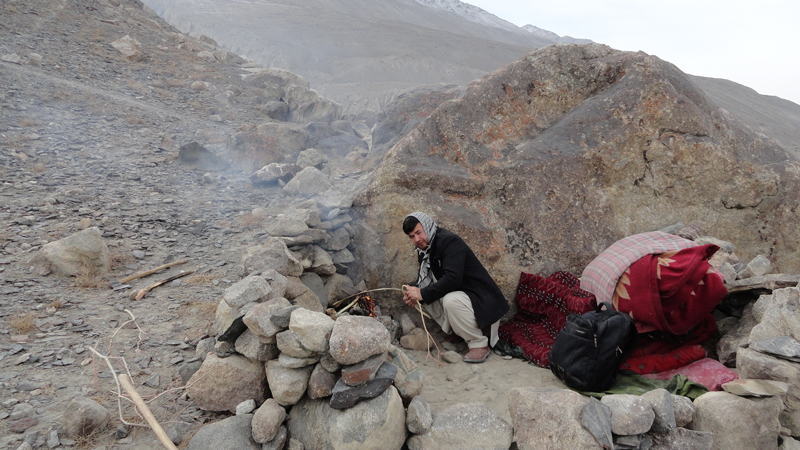 Man starts a fire in a rocky landscape.