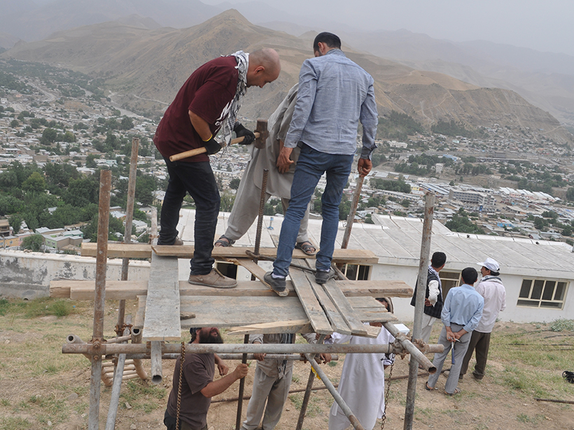Men working on a makeshift platform in front of a populated valley