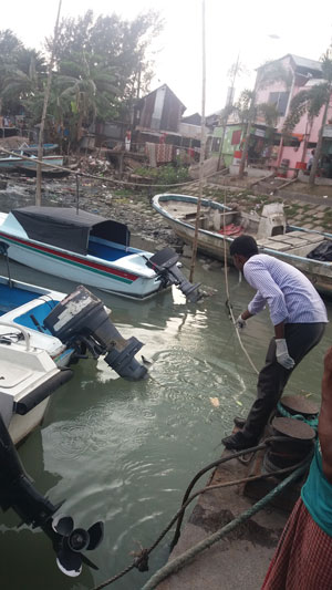 Man samples water in a small, crowded, polluted harbor.