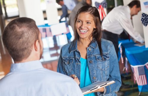 Smiling woman conducts an exit poll at a U.S. polling place.