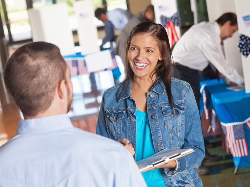 Smiling woman conducts an exit poll at a U.S. polling place.