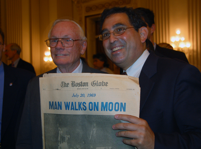 Neil Armstrong poses with Randy Showstack and a Boston Globe front page reading “Man Walks on Moon.”