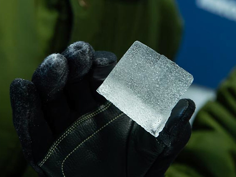 A gloved hand holding an ice core