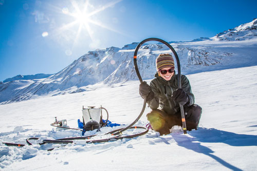 Photo of a smiling woman conducting an experiment on a glacier