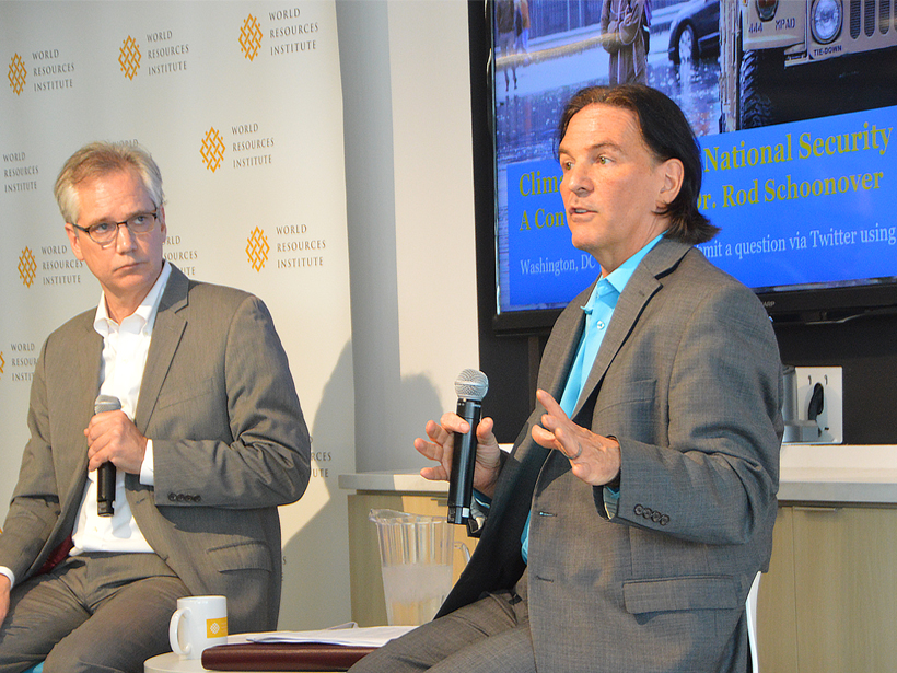Two white men speak at a panel on national security and climate.