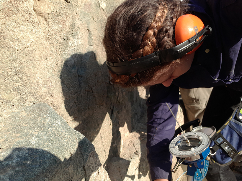 Scientist holding a magnetic instrument over a rock