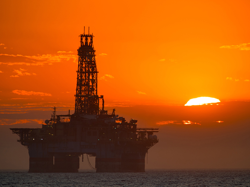 Orange sunset over ocean and offshore oil platform