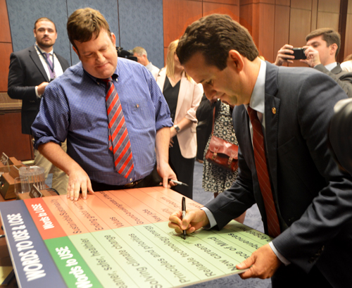 Sen. Brian Schatz (D-Hawaii) signs pollster Frank Luntz’s “Words To Use & Lose” poster after the hearing.