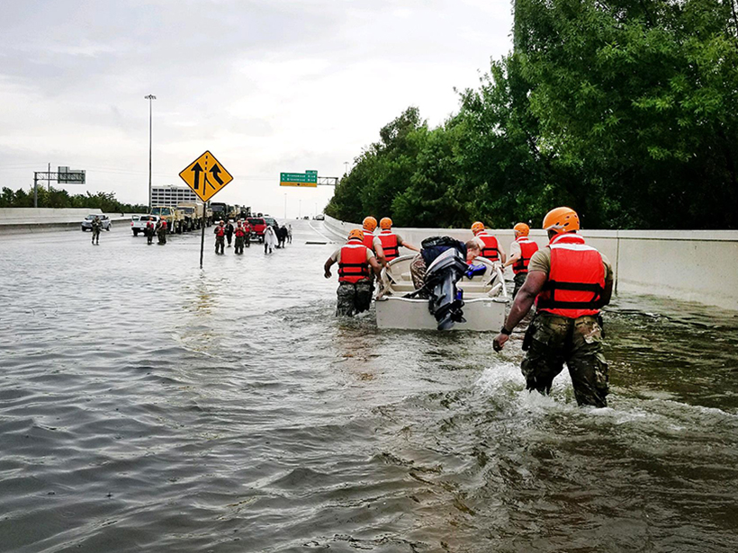 National Guard rescue man in boat on flooded street