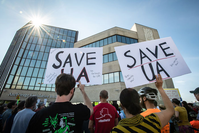 Photo of a protest with “Save UA” signs outside the Anchorage Legislative Building
