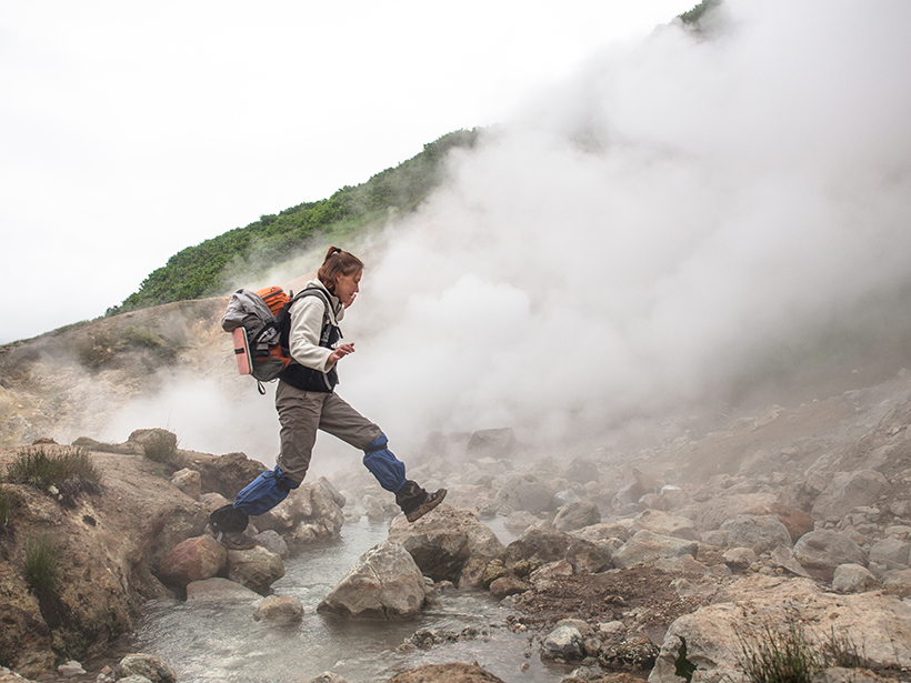 Woman jumping over stream