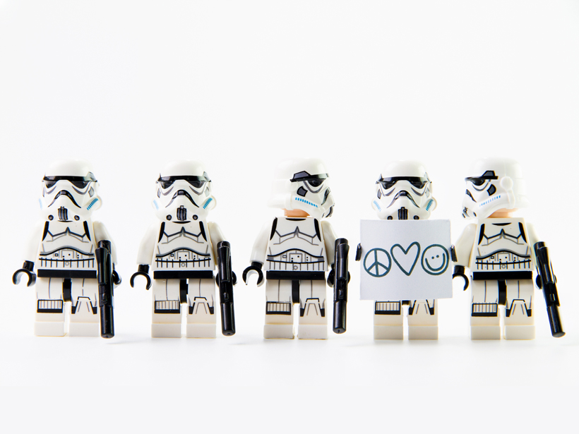 A lineup of five Lego stormtroopers, one carrying a peace/love sign