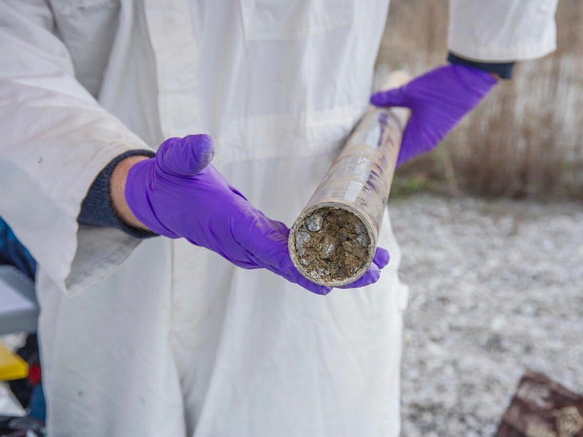 Photo of a man in a lab coat holding a soil core