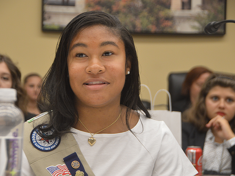Smiling young woman in a Girl Scouts sash speaks before Congress.