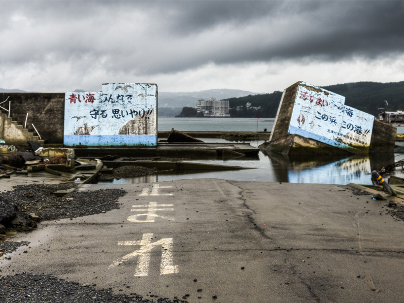 Photo of a destroyed seawall with Japanese writing