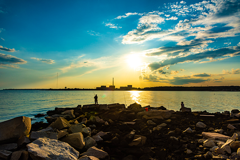 Fishermen fish along a shoreline as the sun sets