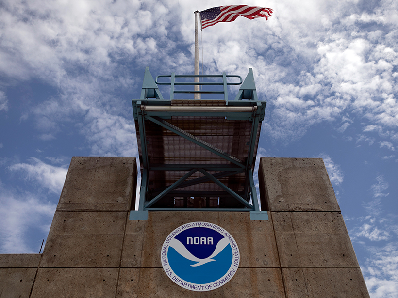 A U.S. flag flies over the NOAA logo at the National Hurricane Center in Miami, Fla.