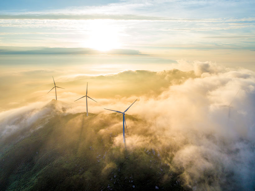 Aerial photo of large wind turbines on a cloudy mountaintop