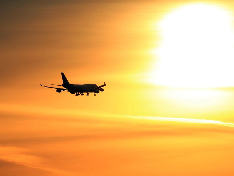 Plane flying into sunset