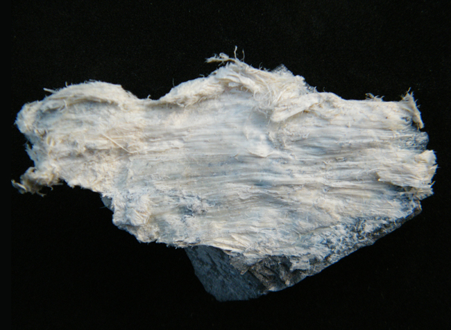 Photo of a fibrous white mineral on a black background
