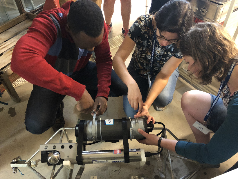 Marine biogeochemists at a workshop last summer huddle over a biogeochemical instrument they are learning to use.